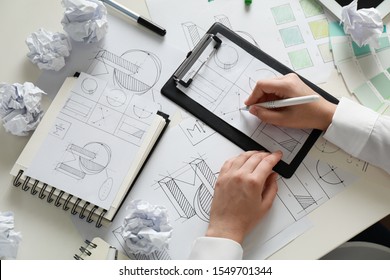 Female designer working at wooden table, top view