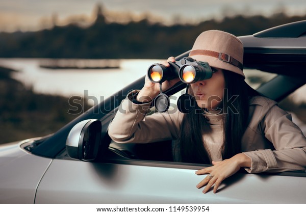 Female Detective Spying with Binocular from a Car.\
Secret agent private investigator looking for evidence in\
infidelity case\

