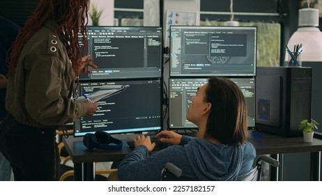 Female developer analyzing program code and talking to asian engineer with chronic disability, collaborating on new interface development. Wheelchair user and app developer programming language. - Powered by Shutterstock - Get 15% off with code: PIKWIZARD15