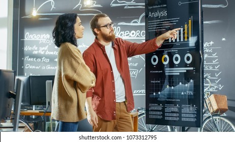 Female Developer and Male Statistician Use Interactive Whiteboard Presentation Touchscreen to Look at Charts, Graphs and Growth Statistics. They Work in the Stylish Creative Office. - Shutterstock ID 1073312795