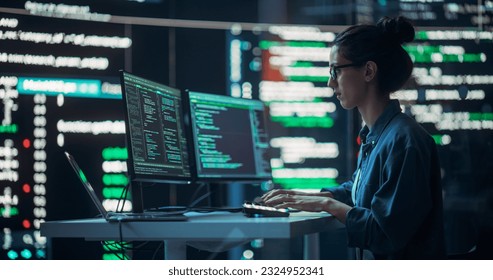 Female Developer Thinking and Typing on Computer, Surrounded by Big Screens Showing Coding Language. Professional Programmer Working in an Office, Running Coding Tests. Futuristic Programming