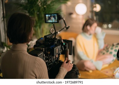 Female Director Of Photography With A Camera On A Movie Set. Professional Videographer On The Set Of A Movie, Commercial Or TV Series. Filming Indoors, Studio