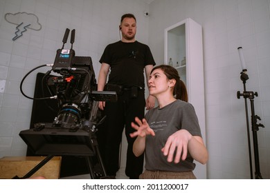 Female Director Of Photography With A Camera On A Movie Set. Professional Videographer On The Set Of A Movie, Commercial Or TV Series. Filming Indoors, Studio