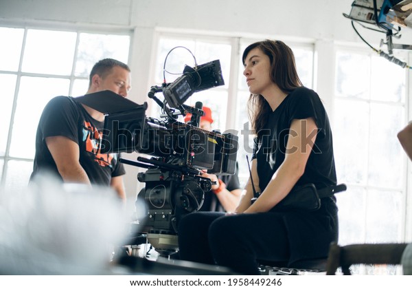 Female director of photography\
with a camera on a movie set. Professional videographer on the set\
of a movie, commercial or TV series. Filming indoors,\
studio