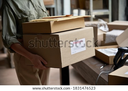Female distribution warehouse worker or seller holding ecommerce shipping order boxes preparing for dispatching, post courier delivery dropshipping commerce retail shipment service concept, closeup.