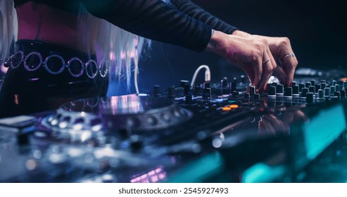 Female DJ Performing Live on Stage, Mixing Tracks With Professional Equipment. Close Up Shots of Hands Adjusting Controls on Decks and Mixers. Captivating Concert Atmosphere With Energetic Beats - Powered by Shutterstock