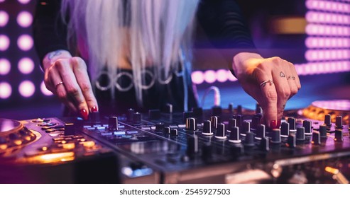 Female DJ Performing Live on Stage, Mixing Tracks With Professional Equipment. Close Up Shots of Hands Adjusting Controls on Decks and Mixers. Captivating Concert Atmosphere With Energetic Beats - Powered by Shutterstock