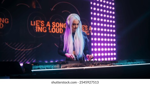 Female DJ Performing Live on Stage, Mixing Tracks With Professional Equipment. Close Up Shots of Hands Adjusting Controls on Decks and Mixers. Captivating Concert Atmosphere With Energetic Beats - Powered by Shutterstock