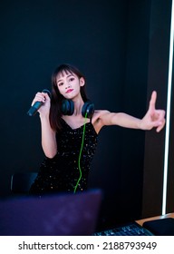 A Female DJ In A Sexy Black Slip Dress Is Playing