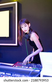 A Female DJ In A Sexy Black Slip Dress Is Playing