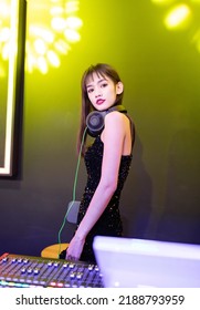 A Female DJ In A Sexy Black Slip Dress Is Playing