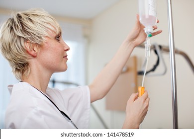 Female Doctor Adjusting Infusion Bottle In Hospital