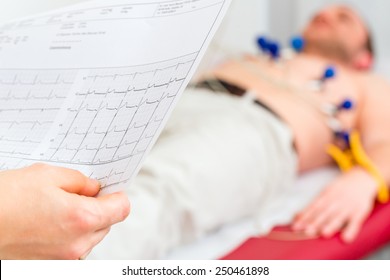 Female Doctor Analyzing ECG Electrocardiogram Of Patient In Hospital