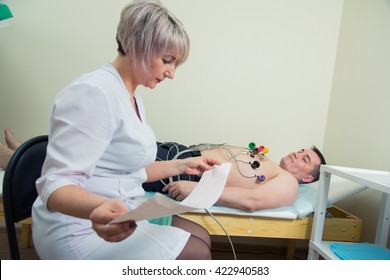 Female Doctor Analyzing ECG Electrocardiogram Of Patient In Hospital.