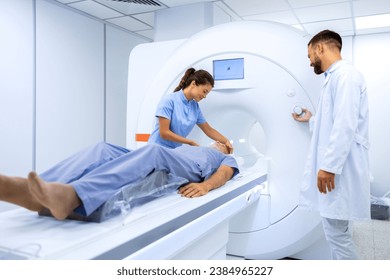 Female doctor assisting senior patient while doing MRI scan in medical examination room. - Powered by Shutterstock