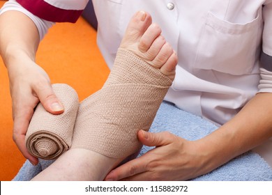 Female Doctor Bandaged Foot Of A Patient