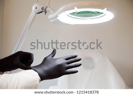 Female doctor beautician wears sterile gloves prepares to receive clients