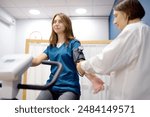 Female doctor cardiologist measures pressure with patient during bicycle exercise for examination cardiovascular system at medical clinic. Young woman training on bike simulator. Exercise bike