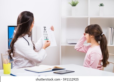 Female Doctor Checking Eyesight Of A  Little Girl At Medical Office.Doctor Doing Eye Exam With Child