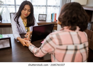 Female Doctor Checking Pulse Of Female Patient Holding Her Wrist In Clinic Room