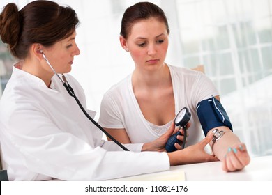 Female Doctor Checking Young Woman Blood Pressure