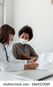 Female Doctor Communicating With A Patient While Wearing Protective Face Mask During Medical Appointment.