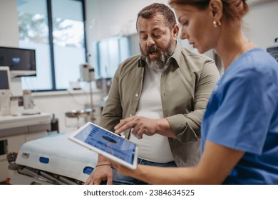 Female doctor consulting with overweight patient, discussing test result in doctor office. Obesity affecting middle-aged men's health. Concept of health risks of overwight and obesity. - Powered by Shutterstock