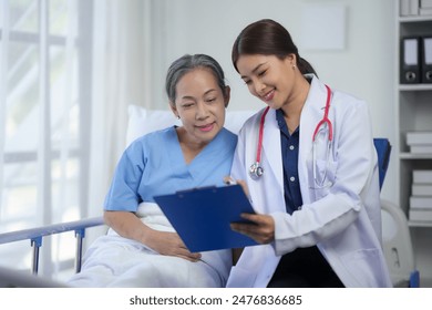 Female doctor consulting with a senior patient in a hospital room, discussing medical records. Healthcare and patient care concept. - Powered by Shutterstock