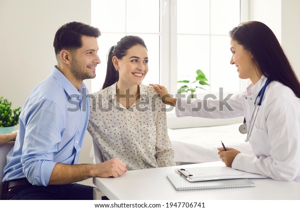 Female doctor consulting young couple\
patients in fertility clinic about IVF or IUI. Doctor encourages\
and assures the young couple that everything will be fine. Concept\
of artificial\
insemination.