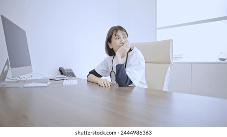 Female doctor deep in thought while sitting at her desk in a medical office - Powered by Shutterstock