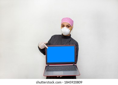 Female Doctor Or Dentist In Surgical Suit And N95 Face Mask Showing Laptop Screen