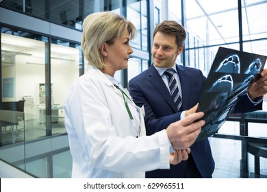 Female doctor discussing x-ray report with businessman in hospital - Powered by Shutterstock