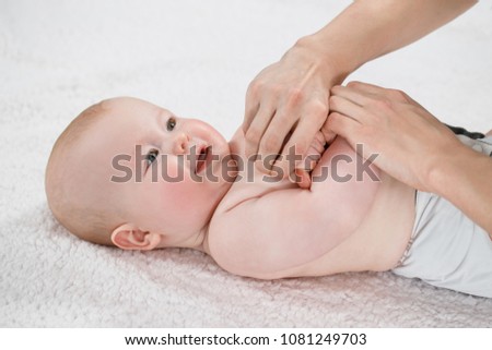 Female doctor doing massage and gymnastic baby on a light background