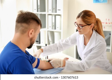 Female Doctor Drawing A Blood Sample Of Male Patient In Clinic