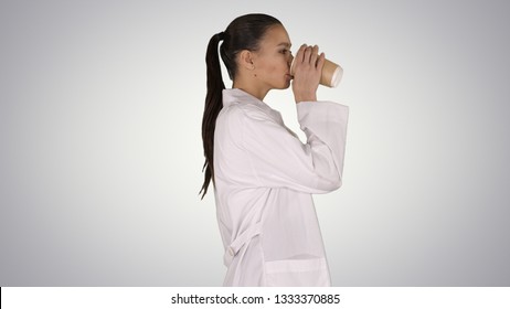 Female Doctor Drinking Coffee And Walking On Gradient Background.