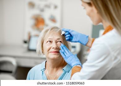 Female doctor dripping eye drops on eyes of a senior patient during a treatment at the ophthalmological office