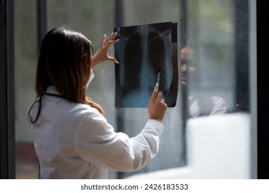 Female doctor examining a chest X-ray film with attention in a modern clinic setting. - Powered by Shutterstock