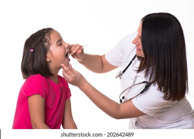 Female Doctor Examining Child With Tongue Depressor At Surgery.