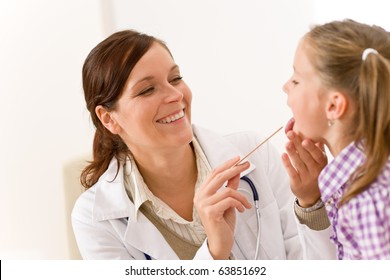 Female Doctor Examining Child With Tongue Depressor At Surgery