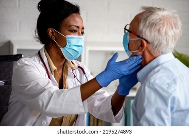 Female Doctor Is Examining Male Elderly Patient At Clinic. Doctor And Patient Wearing A Face Mask.