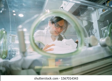 Female Doctor Examining Newborn Baby In Incubator. Night Shift