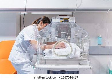 Female Doctor Examining Newborn Baby In Incubator. Night Shift