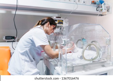 Female Doctor Examining Newborn Baby In Incubator. Night Shift