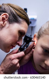 Female doctor examining patient ear with otoscope in hospital