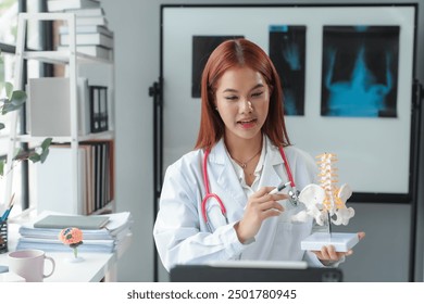 Female doctor explaining spinal anatomy to her online audience using anatomical model of human skeleton during online consultation in her office - Powered by Shutterstock