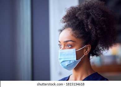 Female Doctor In Face Mask Wearing Scrubs Under Pressure In Busy Hospital During Health Pandemic