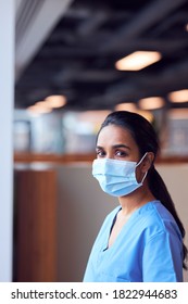 Female Doctor In Face Mask Wearing Scrubs Under Pressure In Busy Hospital During Health Pandemic