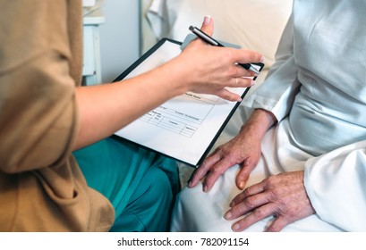 Female Doctor Filling Out A Questionnaire To A Senior Patient