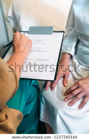 Female doctor filling out a questionnaire to senior patient