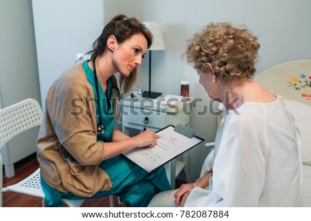 Female doctor filling out a questionnaire to a senior patient